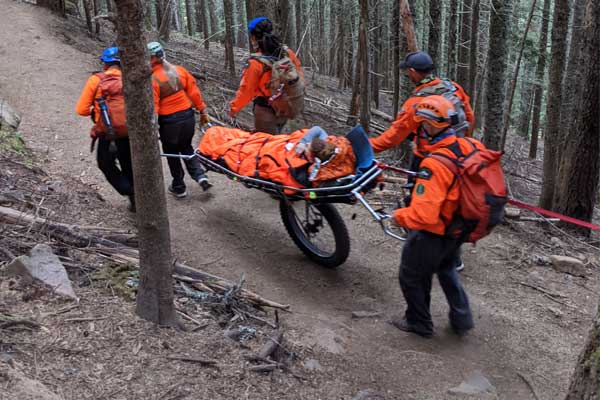 Search and Rescue volunteers move an injured person on a mountain trail