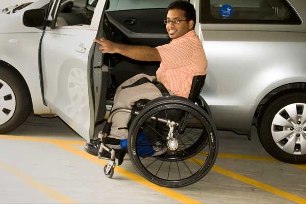 Man with a wheelchair getting into a car