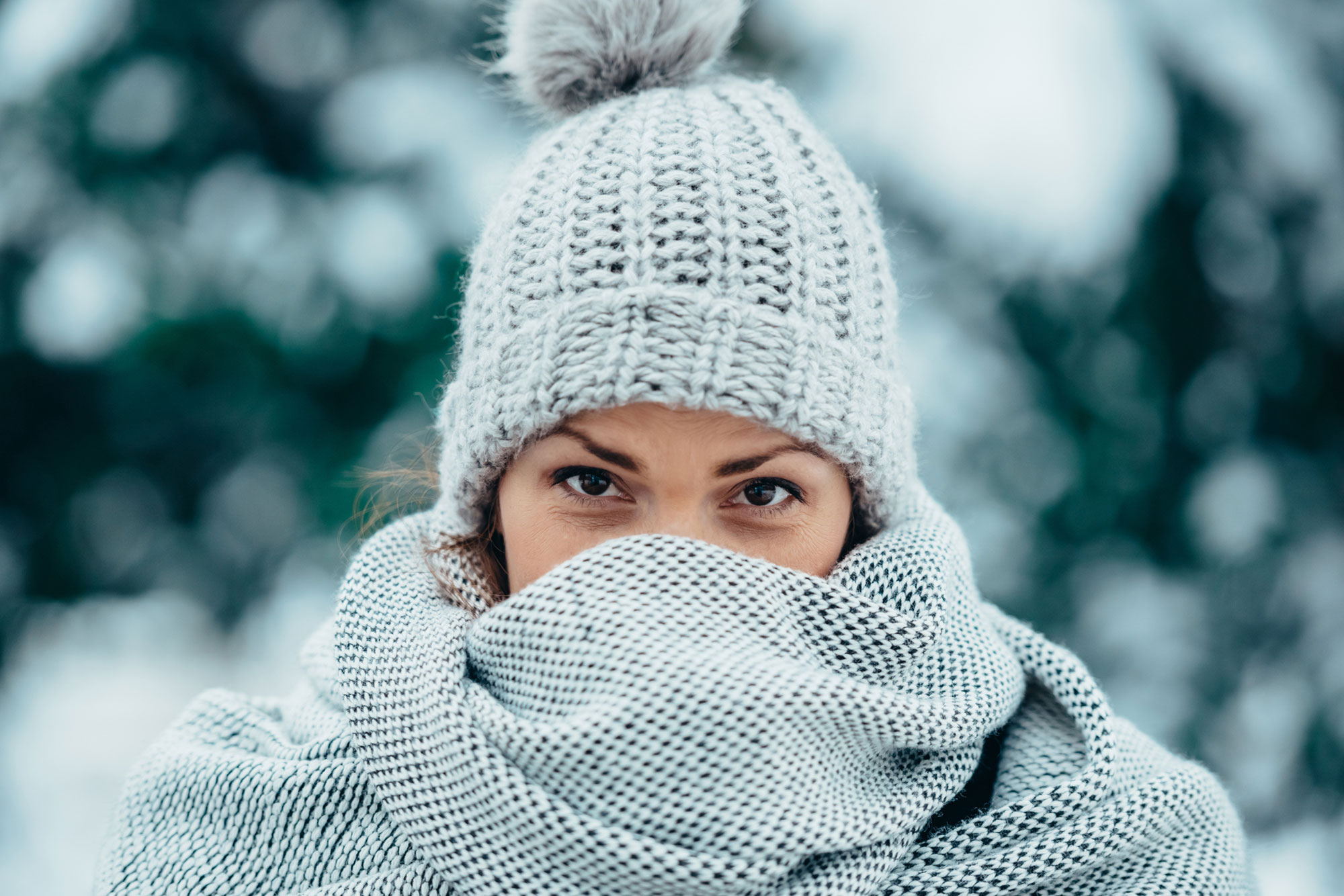 young woman wearing scarf and a a hat on a cold winter day during snow