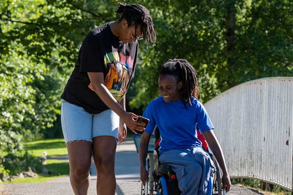 Two friends, one walking and one in a wheelchair