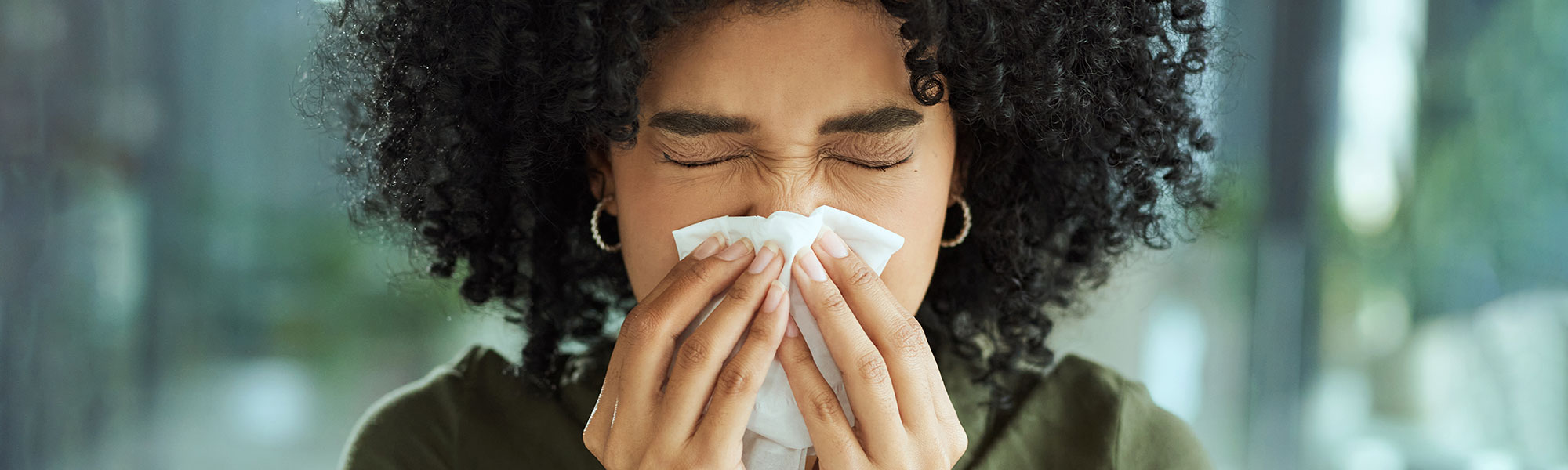 person blowing nose with tissue