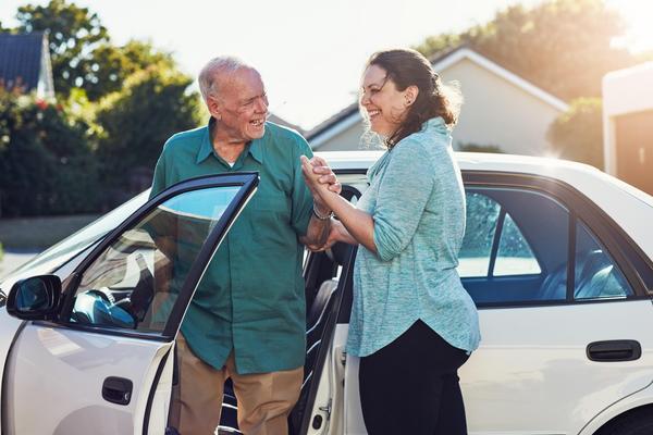 women helping older man in a car