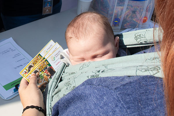 Woman holding a baby while spending her WIC checks at a farmers market