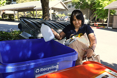 woman putting a plastic bottle in her recycling bin