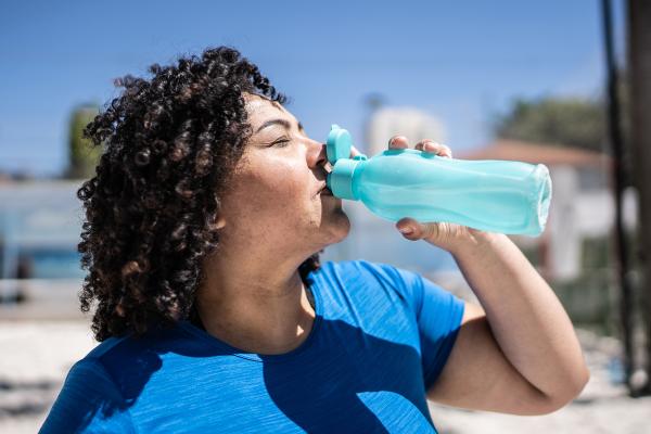 Woman drinking water in a beach volleyball court