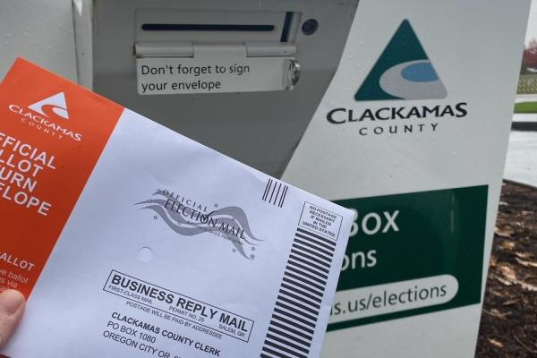 A voter returns their ballot to the Wilsonville official ballot drop site.