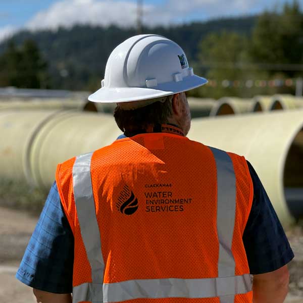 Man with hard hat looks over pipes