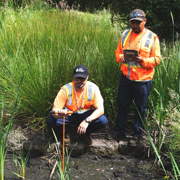 Two field technicians take a soil sample